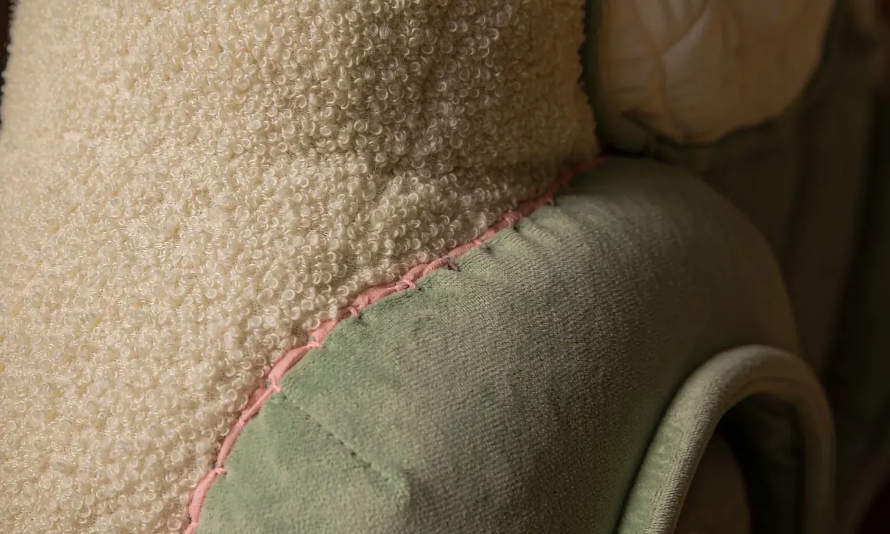 Macro detail of the plush car body: boucle fur, sage plush panel and stitched piping seam