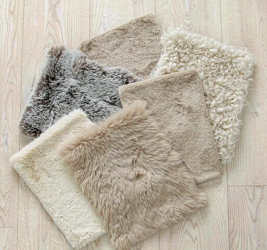 Five faux fur swatches in natural animal tones laid out on an oak table